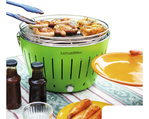 Grătar Lotusgrill cu alimente la grătar, clește grătar, farfurii și sticle de sos.