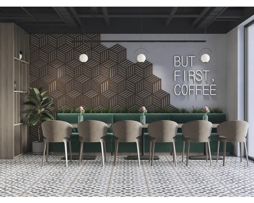 Interiorul unei cafenele cu zonă de relaxare, constând din scaune și mese în fața unui perete cu un model geometric și inscripția mai întâi cafeaua