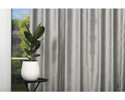 Fereastră decorativă cu perdea și plantă de interior în ghiveci pe o măsuță