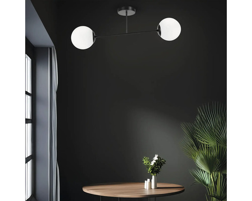 Plafonieră modernă cu două lămpi sferice deasupra unei mese din lemn cu decorațiuni într-o cameră luminoasă.