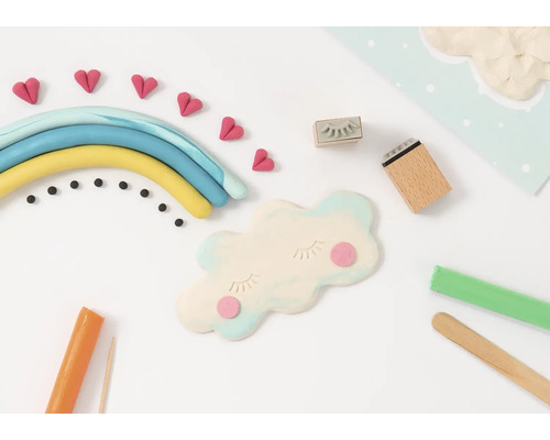 Scenă cu plastilină care înfățișează un curcubeu, nori, inimioare și unelte folosite pentru a crea figurine din plastilină