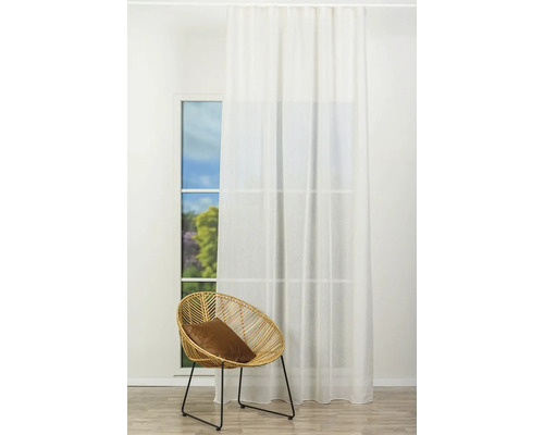 Interior cu fereastră, perdea deschisă la culoare și fotoliu de ratan cu pernă