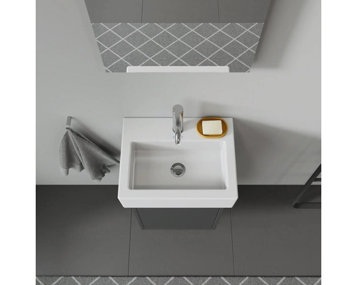 Vedere de sus a unei băi cu chiuvetă, robinet, savonieră și suport pentru prosop