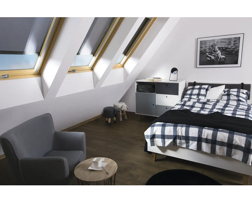 Dormitor luminos la mansardă cu ferestre de mansardă, pat, fotoliu și comodă