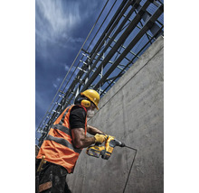 Muncitor în construcții care forează o gaură într-un perete de beton cu un ciocan rotopercutor.