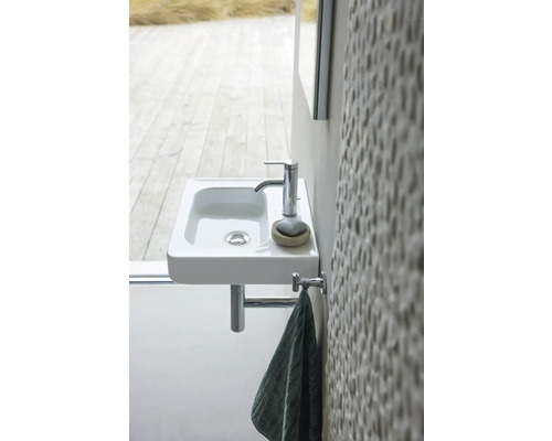 Chiuvetă mică cu robinet și suport pentru prosop în baie.