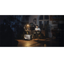 Bărbat lucrând la birou cu centrală electrică portabilă în cameră