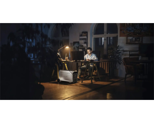 Bărbat lucrând la birou cu centrală electrică portabilă în cameră