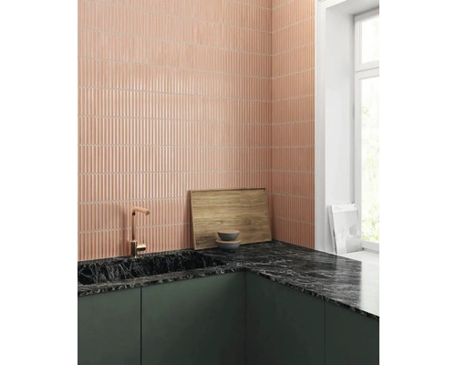 Scenă de bucătărie cu plăci de perete roz alungite, blat negru și chiuvetă