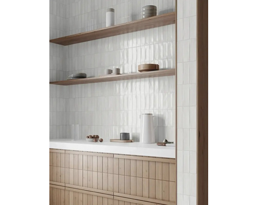 Baie luminoasă cu faianță verticală albă, rafturi din lemn și dulap sub chiuvetă