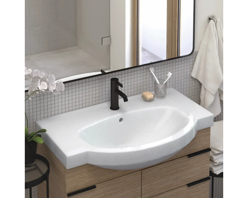 Baie modernă cu lavoar, robinet, oglindă și dulap inferior din lemn.