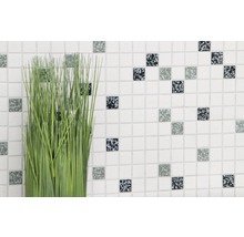 Plantă artificială decorativă în fața unui perete cu plăci mici de mozaic