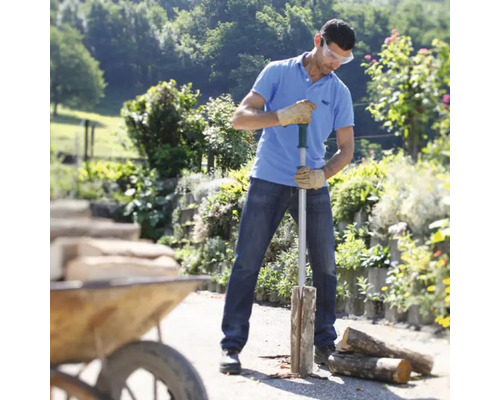 Bărbat care taie lemne cu un despicător de lemne în grădină.