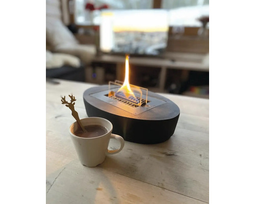 Șemineu decorativ cu etanol cu cană și lingură pe o masă