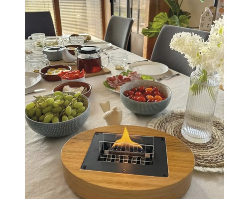 Masa de sufragerie aranjată cu șemineu de masă, veselă, mâncare și vază cu flori