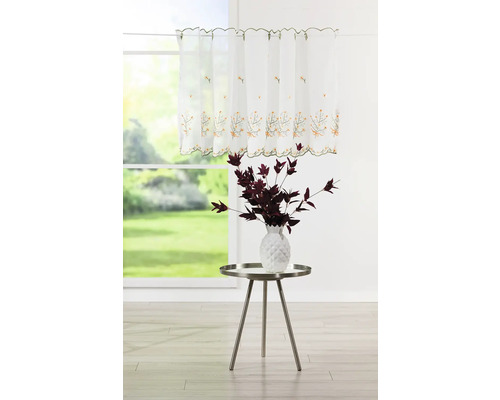 Storila scurtă decorativă, albă, cu broderii florale și o vază cu plante pe o măsuță laterală în fața ferestrei