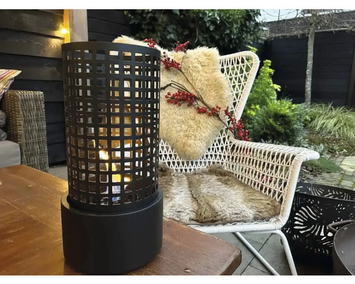 Șemineu de masă cu model grilaj pe o masă de lemn, mobilier de grădină în fundal