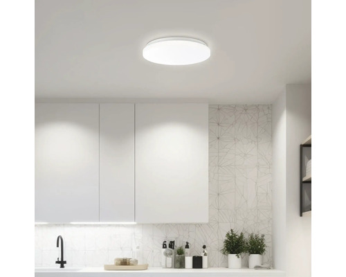 Plafonieră într-o bucătărie luminoasă cu dulapuri și blaturi albe.