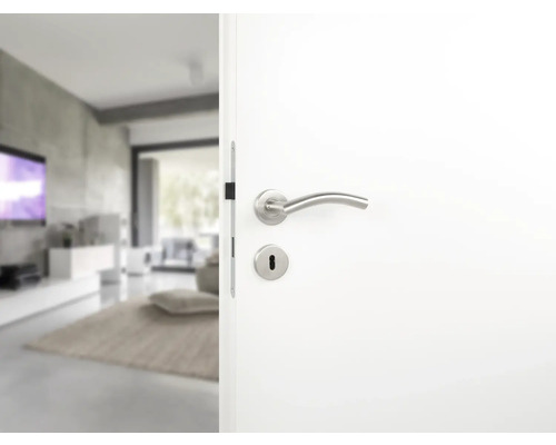 Ușă interioară albă cu mâner și broască care duce într-un living modern