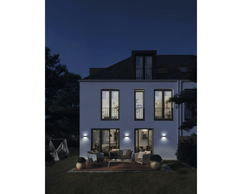 Fațadă de casă cu iluminat exterior, terasă și mobilier de grădină pe timp de noapte