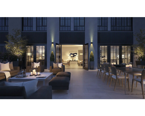 Terasa mare cu mobilier de relaxare, masă și decorațiuni pe timp de noapte.