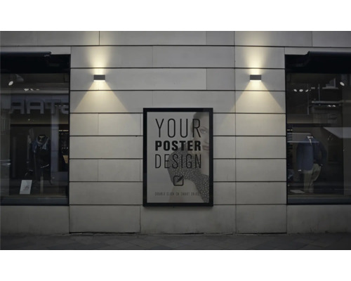 Un afiș înrămat atârnă pe o fațadă între două vitrine cu iluminare exterioară