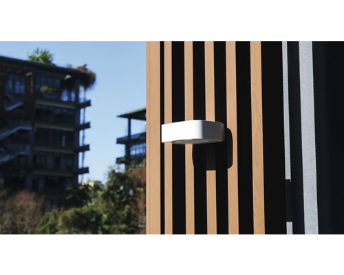 O lampă de exterior albă este fixată pe o fațadă din lemn.