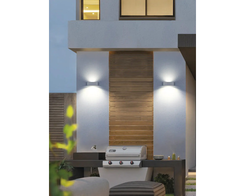 Spațiu exterior cu grătar, aplice de perete și elemente din lemn.