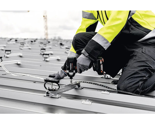 Un meșter montează un sistem solar pe un acoperiș cu o șurubelniță cu impact cu acumulator Metabo.