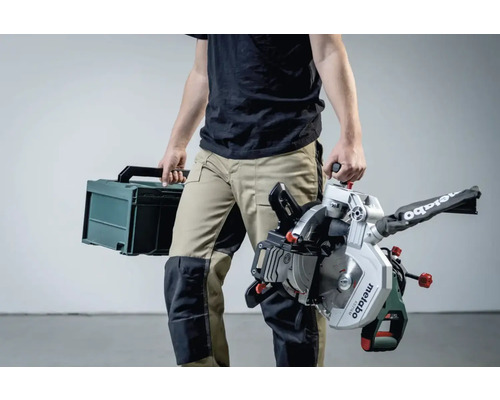 O persoană care transportă un ferăstrău circular Metabo și o cutie de scule.