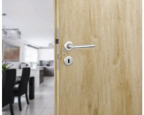 Ușă interioară deschisă cu mâner și încuietoare în fața unei sufragerii și a unei bucătării