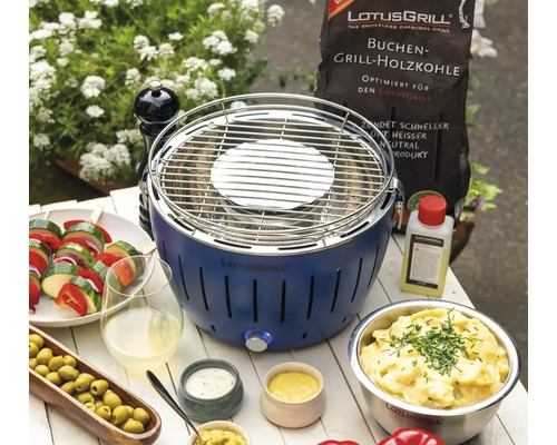 Grătar cu cărbune Lotusgrill cu cărbune, aprinzător și salate pe o masă