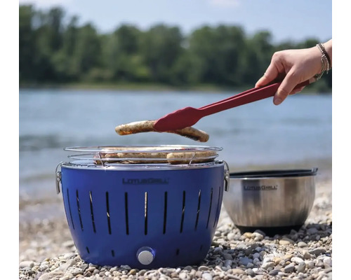 Grătar Lotus albastru cu produse la grătar și clește de grătar pe malul lacului