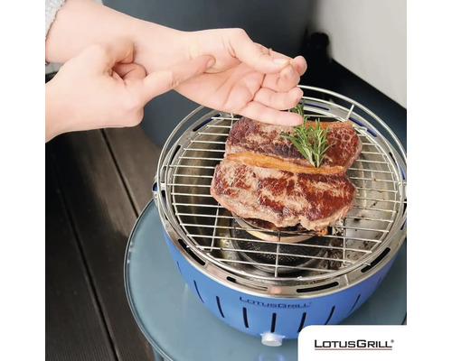 Grătar cu cărbune Lotusgrill cu friptură și rozmarin pe grătar