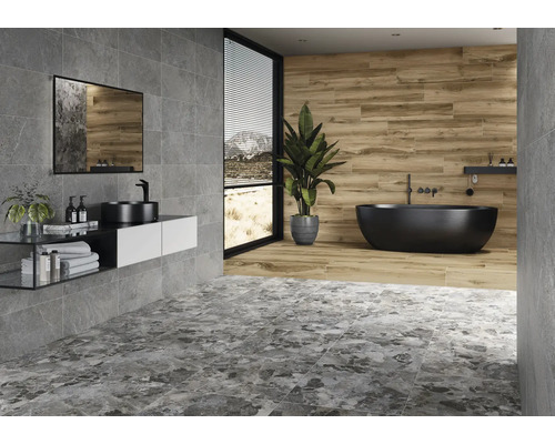 Baie cu gresie gri și maro, chiuvetă, oglindă și cadă independentă.