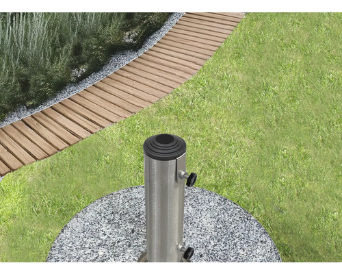 Scenă de grădină cu gazon, plăci de trotuar și un suport pentru umbrelă de soare din granit și metal.