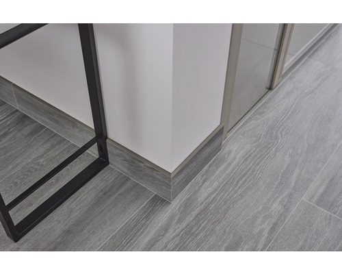 Prim-plan cu podea laminată cu aspect de lemn gri și plinte