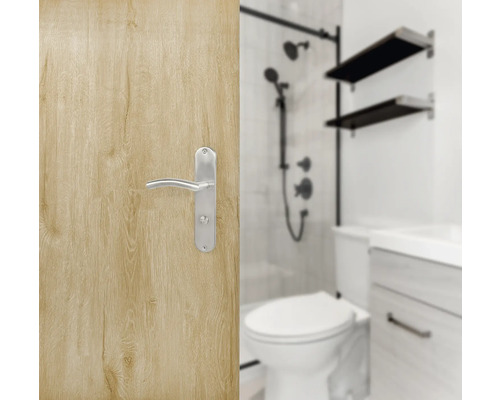 Ușă din lemn deschis la culoare cu clanță argintie și baie în fundal