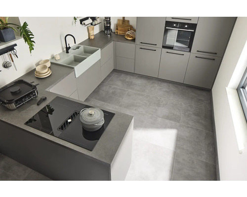 Bucătărie luminoasă cu dulapuri încorporate, chiuvetă, plită și podea cu gresie.