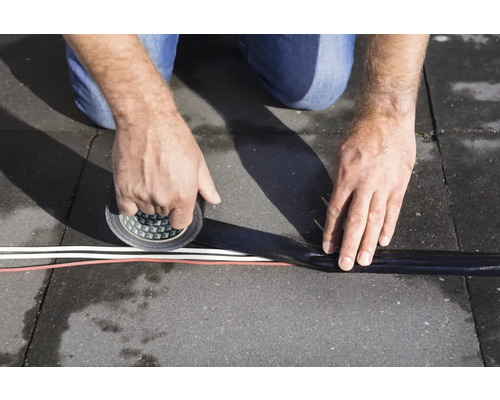 O persoană fixează cabluri cu bandă adezivă pe un substrat.