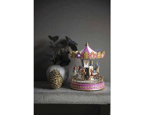 Carusel decorativ cu iluminare, vază și con de pin pe o masă