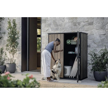 Femeie cu câine în fața unui dulap de scule deschis în aer liber