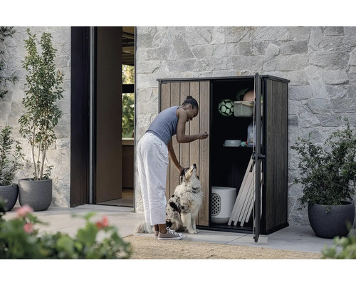 Femeie cu câine în fața unui dulap de scule deschis în aer liber