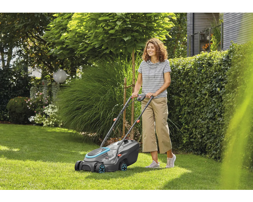 Femeie folosind mașina de tuns iarba în grădină