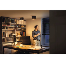 Un birou elegant cu birou, raft, plafoniere și o persoană la fereastră.