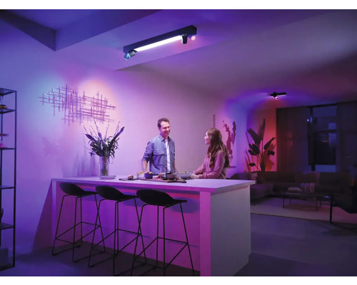 Cameră de zi cu lumini de tavan și două persoane la un bar de bucătărie