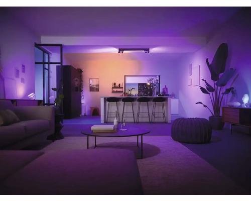 Cameră de zi cu canapea, masă, scaune de bar și iluminat inteligent pentru o ambianță plăcută.