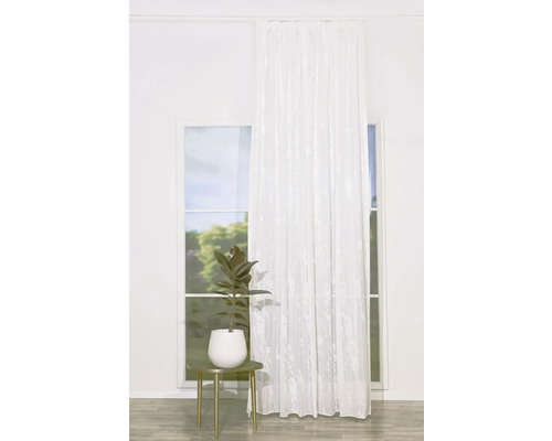 Scenă cu o cortină albă în fața unei ferestre și o plantă pe o masă.