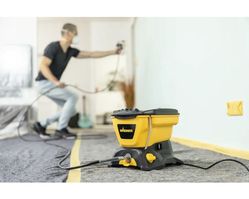 Sistem de pulverizare a vopselei cu un bărbat pulverizând un perete în interior