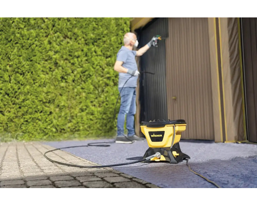 Bărbat care vopsește o ușă de garaj cu un sistem de pulverizare a vopselei Wagner